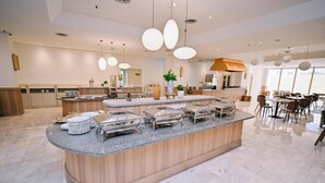 Un moderno vestíbulo de hotel con un mostrador central tipo isla, zona de estar y cocina al fondo.