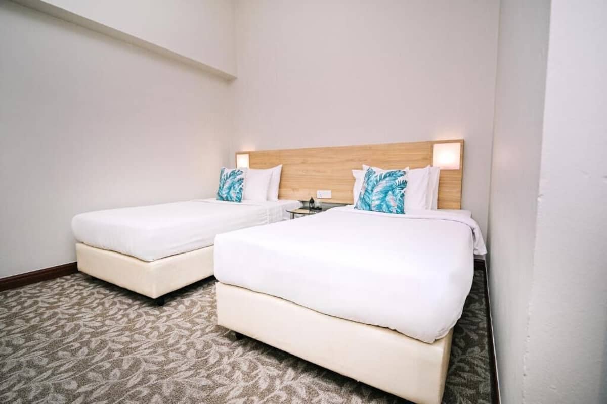 Une chambre d’hôtel avec deux lits, une tête de lit en bois et une moquette à motifs.