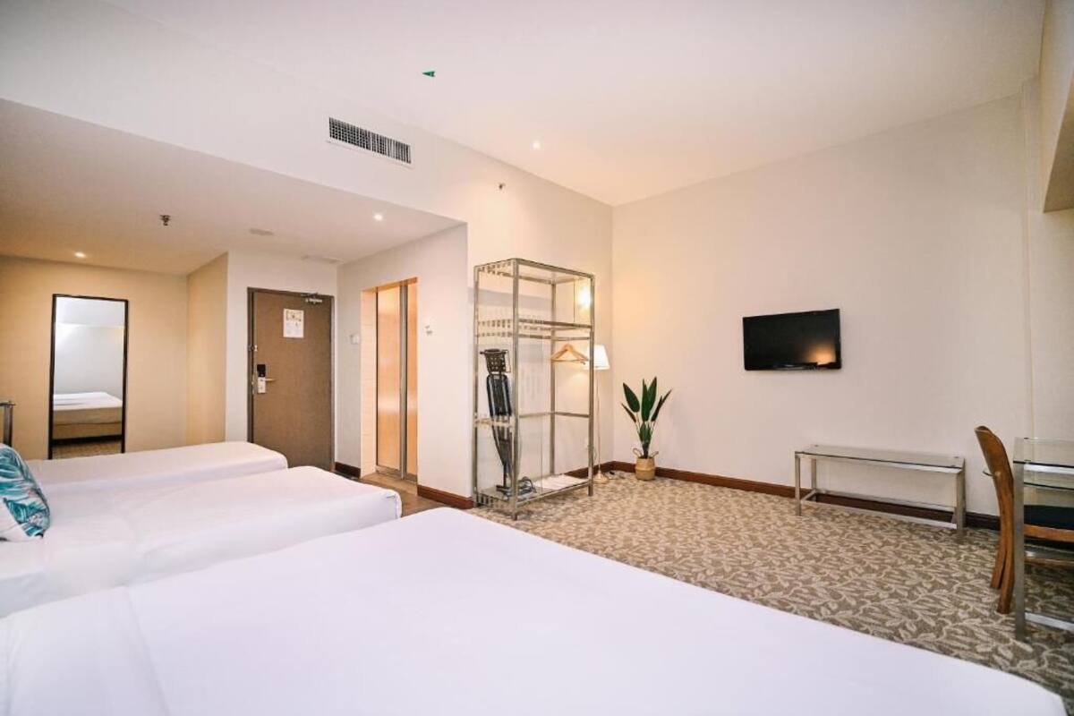 Une chambre d’hôtel avec deux lits, un coin salon, une télévision et un porte-manteau.