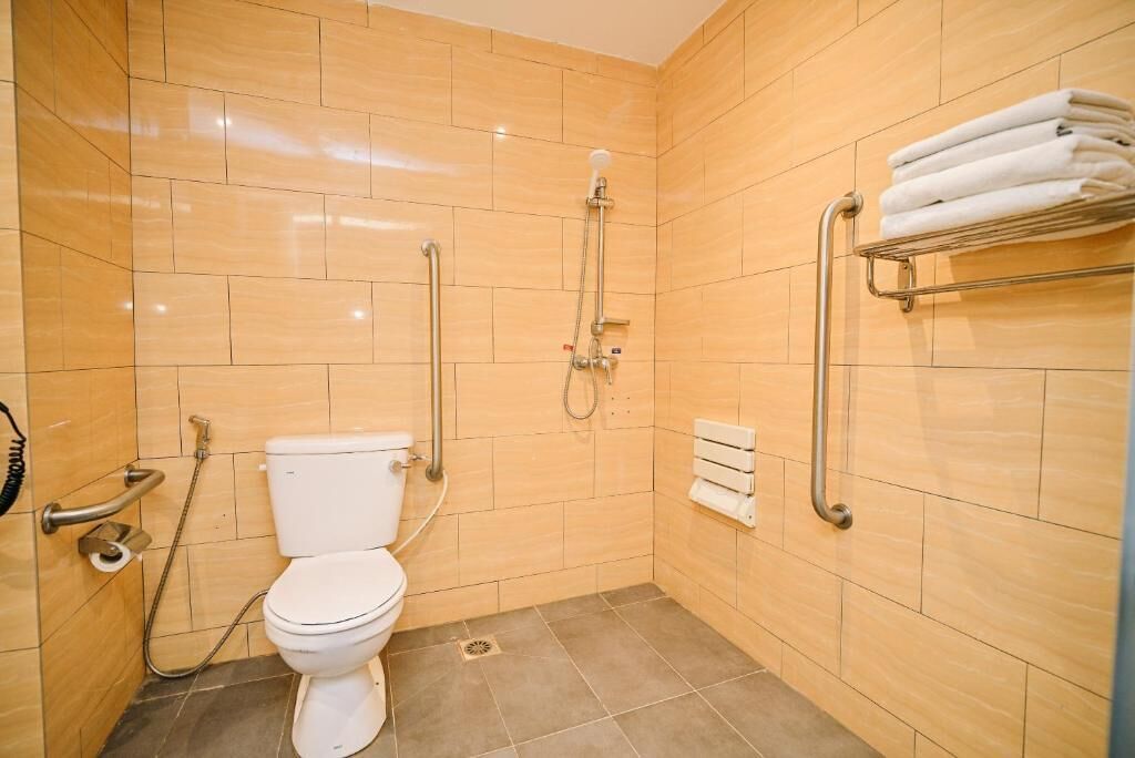 A small, modern bathroom with a toilet, a shower, and a towel rack.