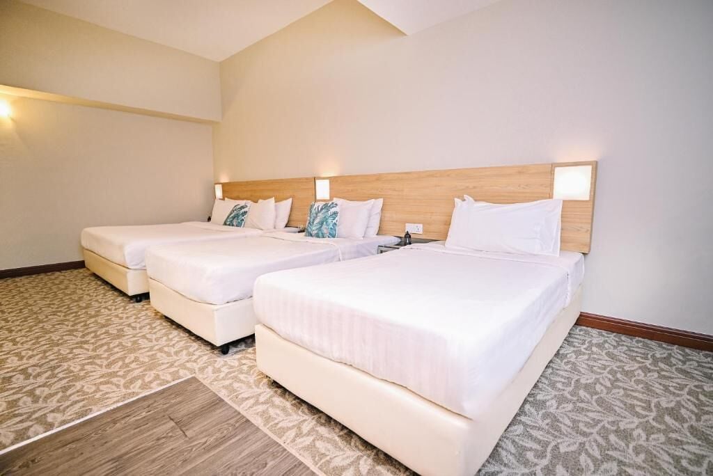 Quarto de hotel com duas camas de solteiro, cabeceira de madeira e carpete estampado.