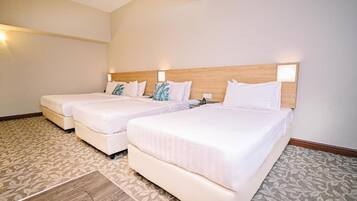Quarto de hotel com duas camas de solteiro, cabeceira de madeira e carpete estampado.
