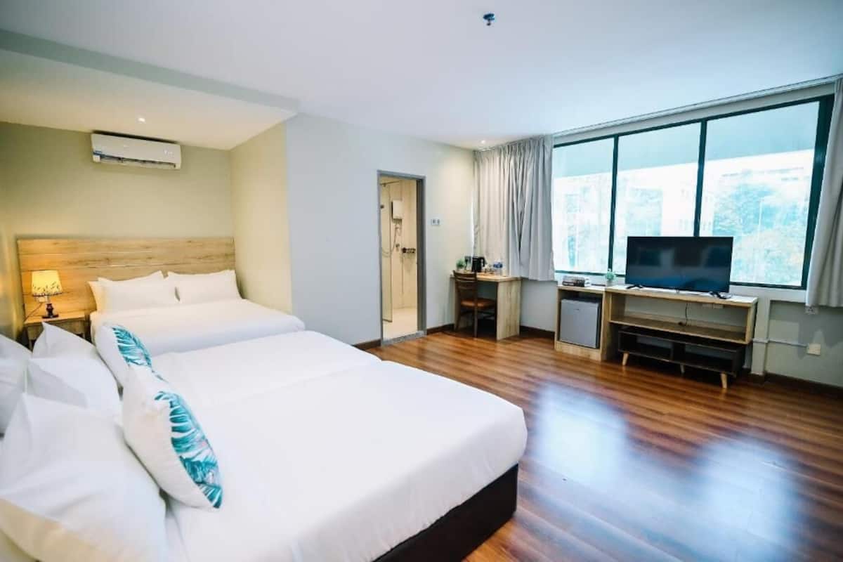Habitación de hotel con una cama grande, un escritorio con televisor y una ventana con cortinas.