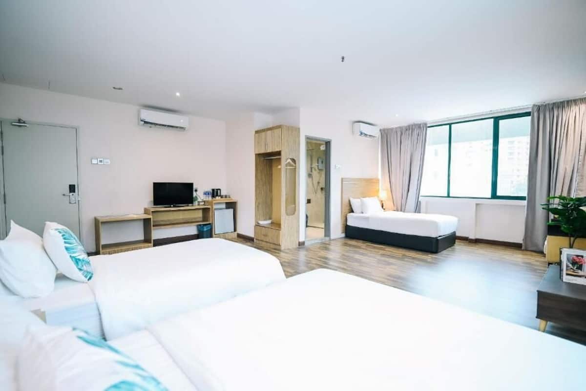 Habitación de hotel con dos camas, un escritorio con televisor, armario y un amplio ventanal con cortinas.