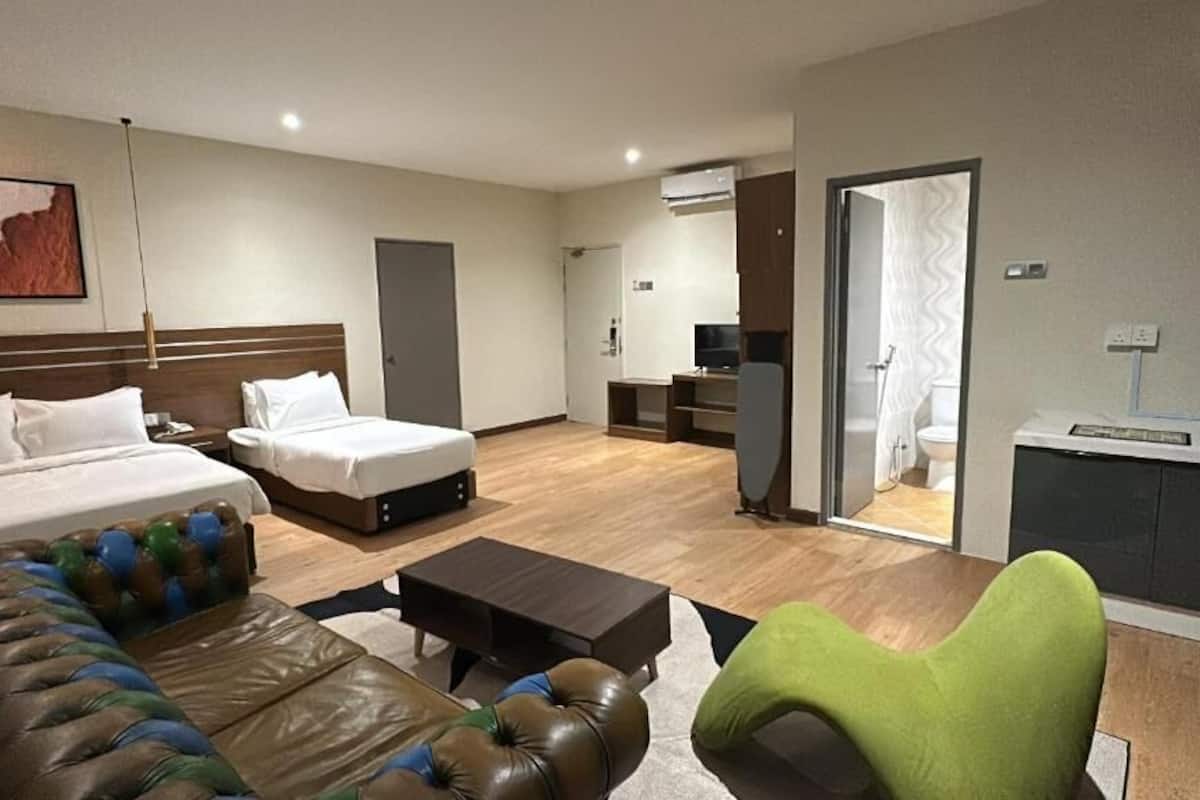 Una habitación de hotel con una cama, un sofá, una mesa de centro y un televisor.