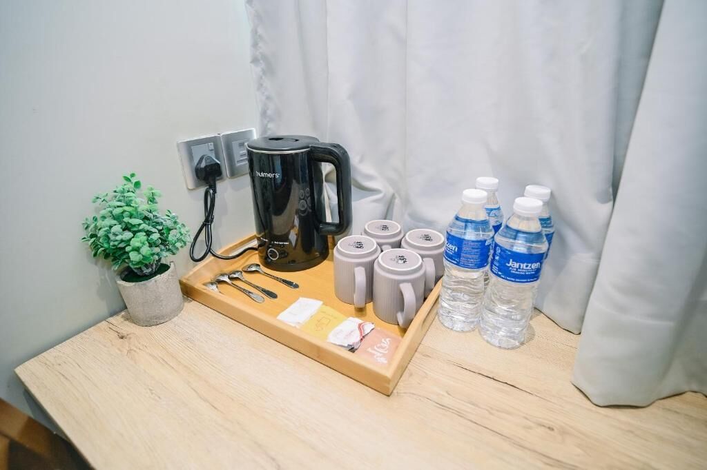 Una bandeja de madera con una tetera, tazas y botellas de agua sobre una mesa.