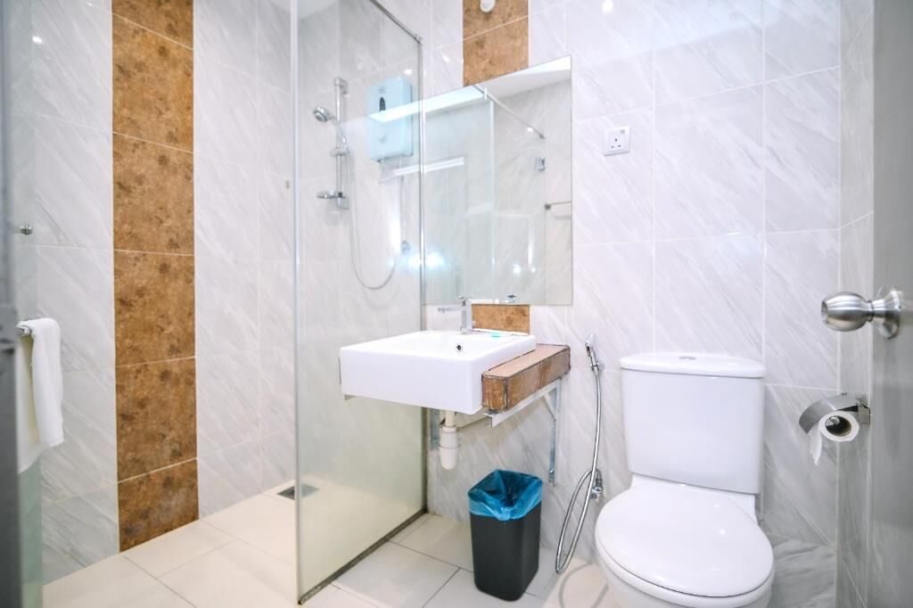 Un baño con mampara de vidrio, un lavamanos blanco y un inodoro.