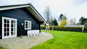A house with a paved patio, a swing set, and a well-maintained lawn.