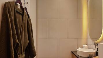A modern bathroom with a large mirror, a round sink, and a wooden vanity.