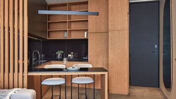 Une cuisine moderne avec des meubles en bois, un plan de travail noir et des tabourets de bar.