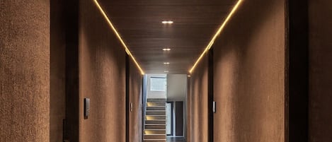 A long, narrow hallway with a wooden floor and walls, leading to a staircase.