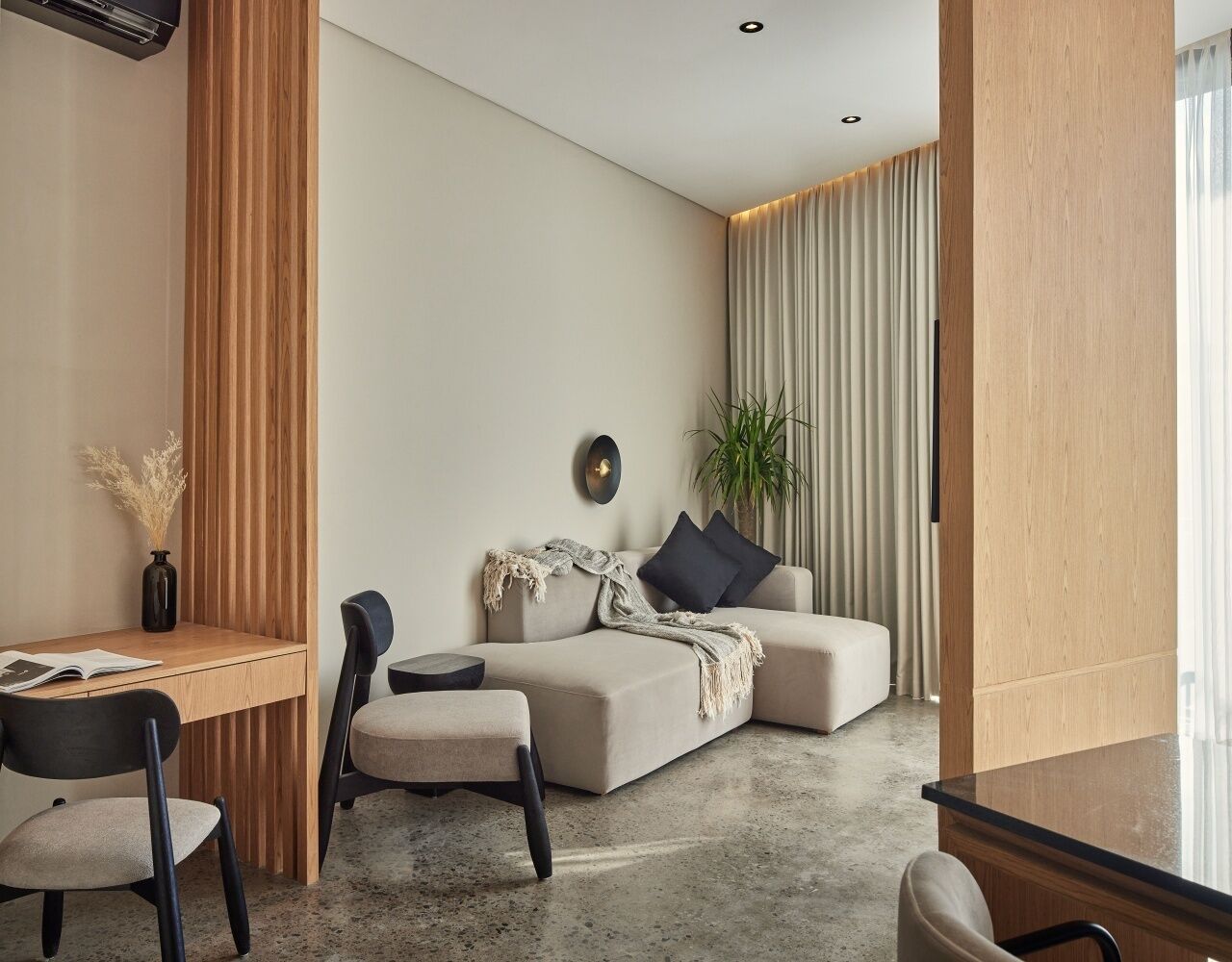 A modern living room with a sofa, a coffee table, and a dining area with a table and chairs.