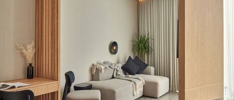 A modern living room with a sofa, a coffee table, and a dining area with a table and chairs.
