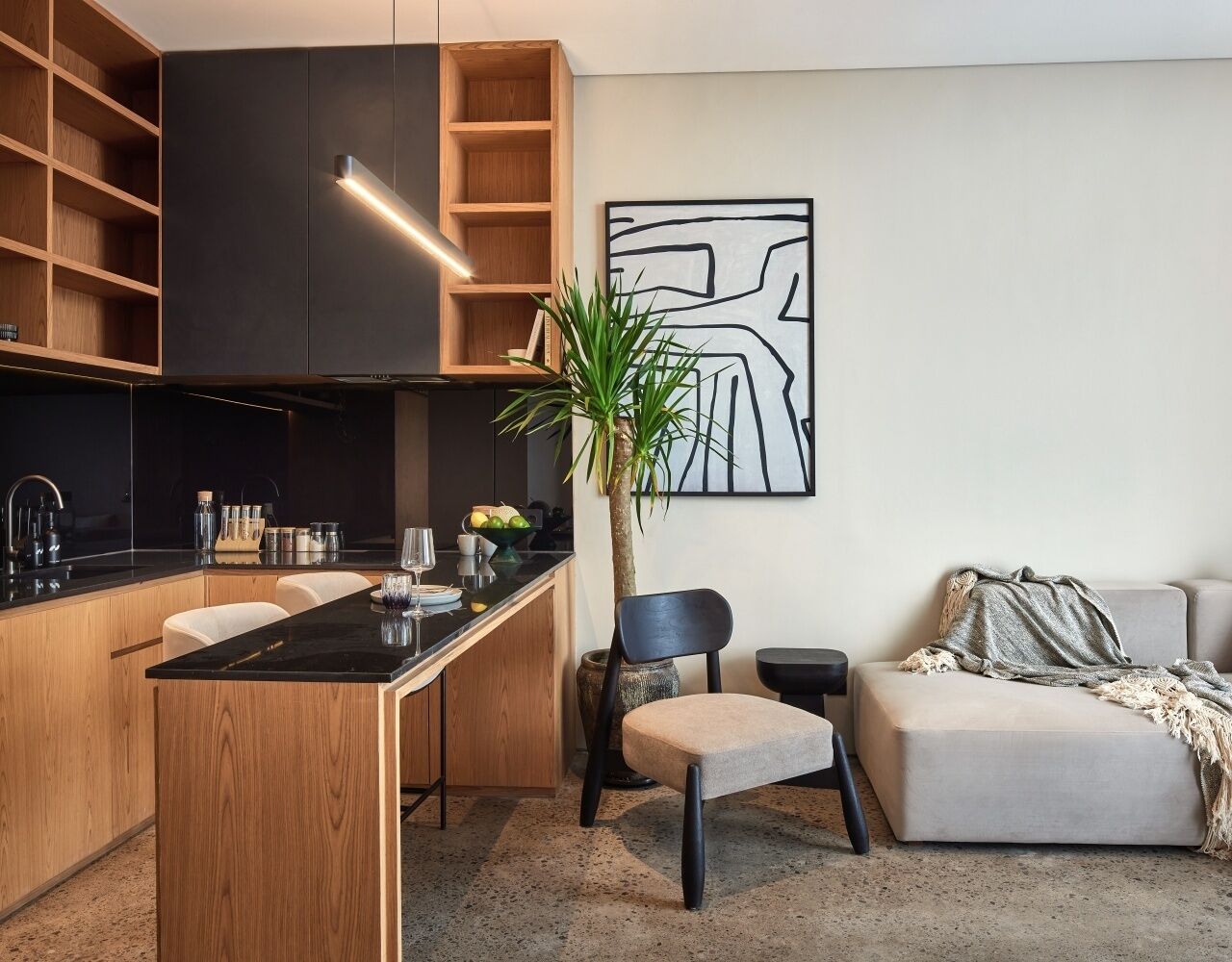 Una cocina moderna con una isla central, estantes de madera y un comedor con sillas.