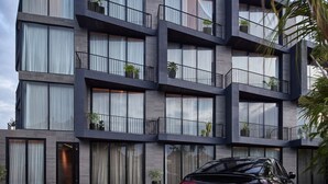 En moderne bygning med flere etager, altaner, store vinduer og plantekasser.
