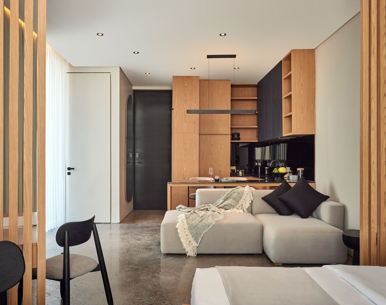 A modern living room with a sofa, a dining table, and a kitchen area.