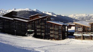 A modern building with large windows and a snowy mountain backdrop. - 2-room Duplex Apartment for 7 People, at the Foot of the Slopes and Shops, Close to the ESF and the Nursery in the Villa (Bourg-Saint-Maurice)