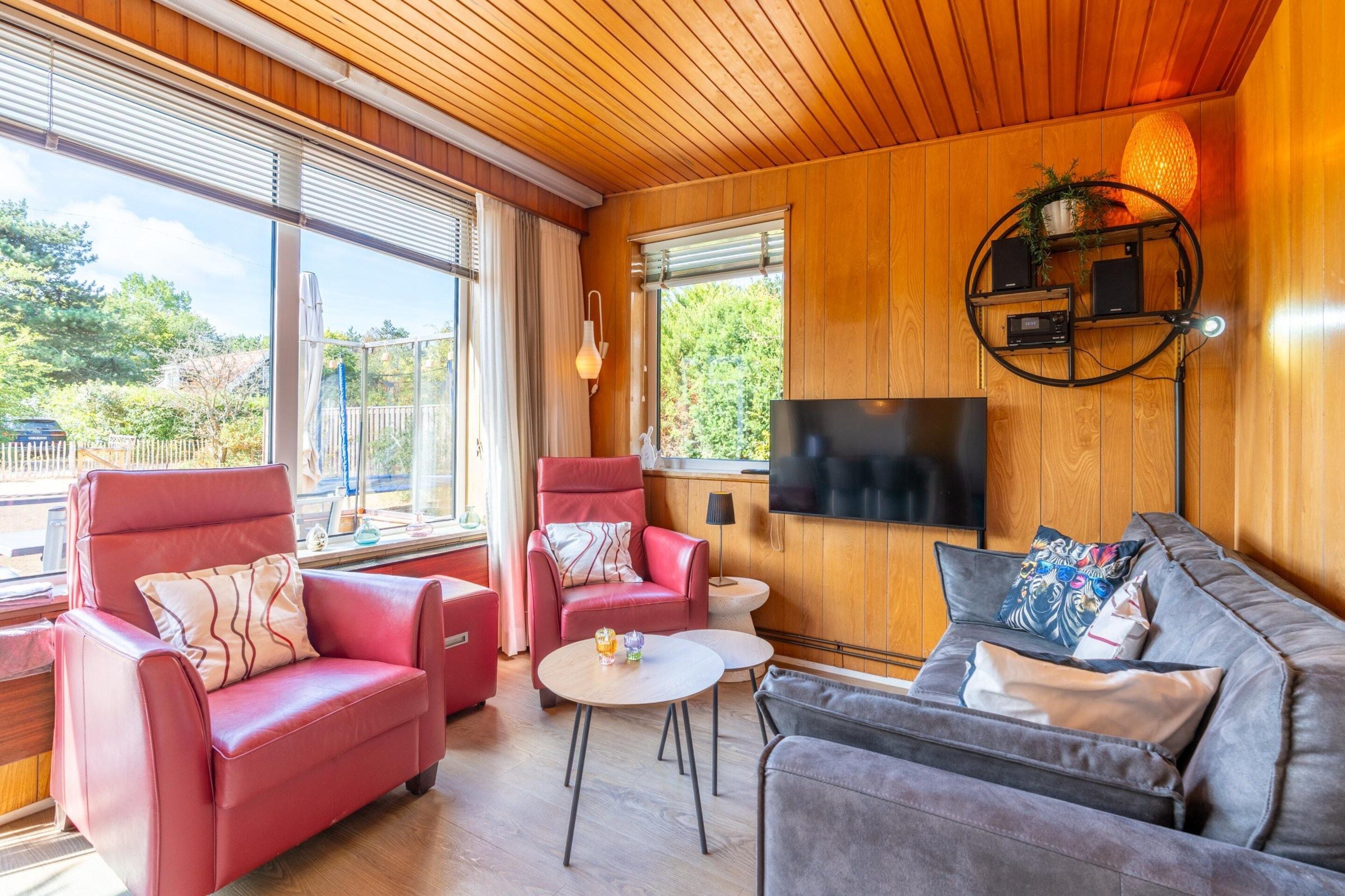 Un salon moderne avec des canapés en cuir, un téléviseur à écran plat et un plafond en bois.