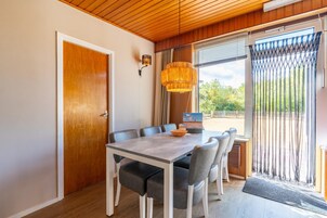 Un espace repas avec un plafond en bois, une table entourée de chaises et une vue par la fenêtre.