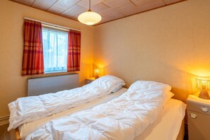 A bedroom with two single beds, a window with curtains, a bedside lamp, and a ceiling light fixture. - Bungalow for 6 Persons With a Very Spacious South-facing Garden (De Koog)