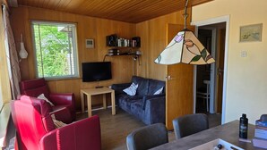 A cozy living room with a red sofa, a grey sofa, a TV, and a wooden ceiling. - Bungalow for 6 Persons With a Very Spacious South-facing Garden (De Koog)
