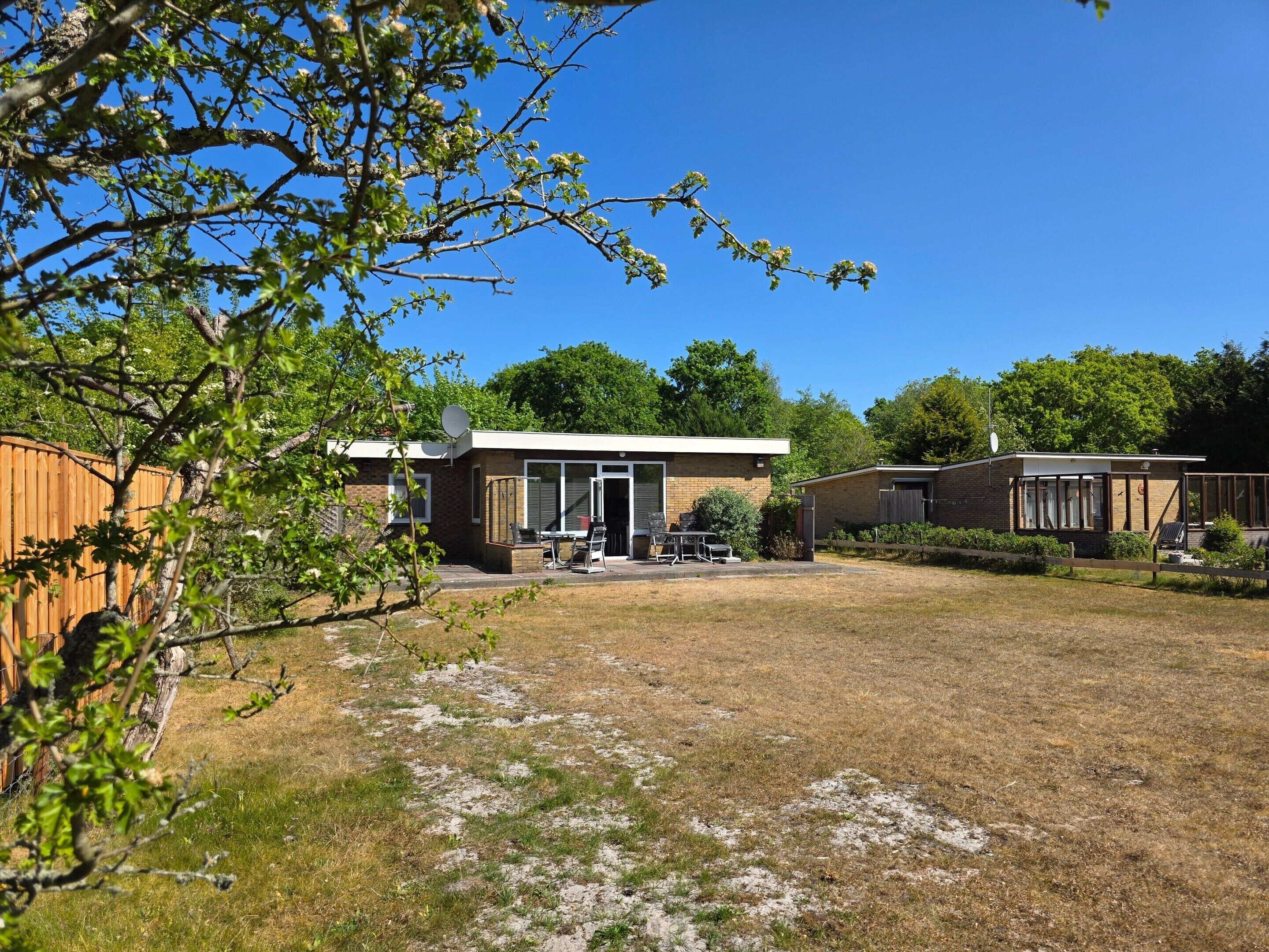 A two-story building with a patio area, a fenced yard, and a wooden fence.