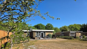 A two-story building with a patio area, a fenced yard, and a wooden fence. - Bungalow for 6 Persons With a Very Spacious South-facing Garden (De Koog)