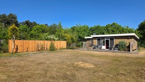 A modern single-story house with a patio area, a wooden fence, and a backyard. - Bungalow for 6 Persons With a Very Spacious South-facing Garden (De Koog)