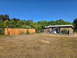 A modern single-story house with a patio area, a wooden fence, and a backyard. - Bungalow for 6 Persons With a Very Spacious South-facing Garden (De Koog)