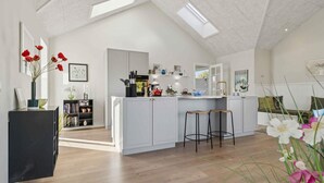 A modern kitchen with a central island, wooden flooring, and skylights. - 4 Star Holiday Home in Svaneke (Svaneke)