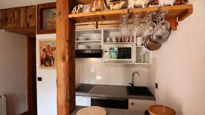 Eine kleine Küche mit Mikrowelle, Spüle und Holzregalen.