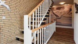 A staircase with white railings and a brick wall. - Ferienwohnung 70qm mit Balkon in Bensersiel (Esens)