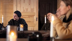 Un interior de madera con una mesa dispuesta para una comida, con velas y una copa.