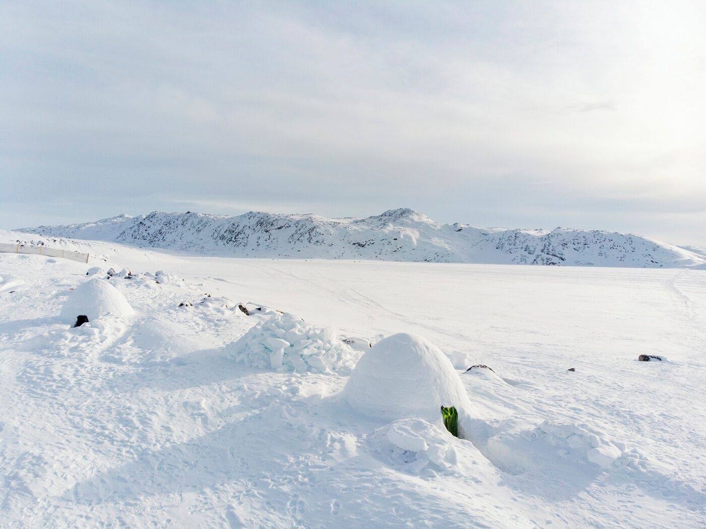 A snowy landscape with a clear sky and distant mountains.