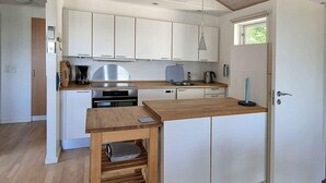 A modern kitchen with white cabinets, a wooden countertop, and a built-in oven.
