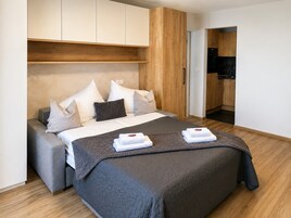 Ein modernes Hotelzimmer mit einem großen Bett, einem fest eingebauten Schreibtisch und einer Küchenzeile.