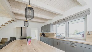 Une cuisine moderne dotée d’un grand îlot central, de meubles gris et d’une fenêtre offrant une belle vue.