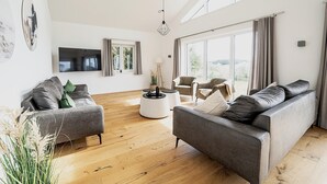 Un salon spacieux doté d’une grande fenêtre, d’un téléviseur à écran plat et d’un ensemble de meubles modernes.