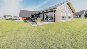 Une maison moderne dotée d’un grand patio, d’un coin repas et d’un garage.