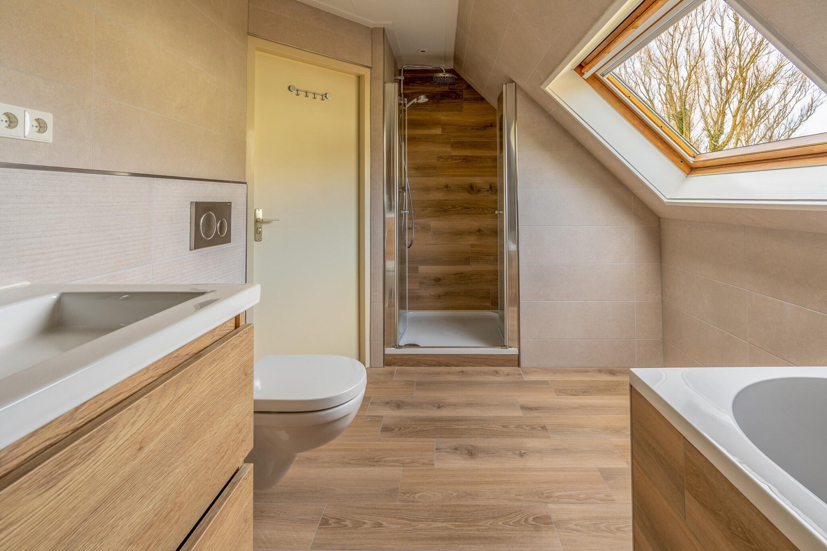 A modern bathroom with a shower, toilet, and bathtub, featuring wooden flooring and a skylight.