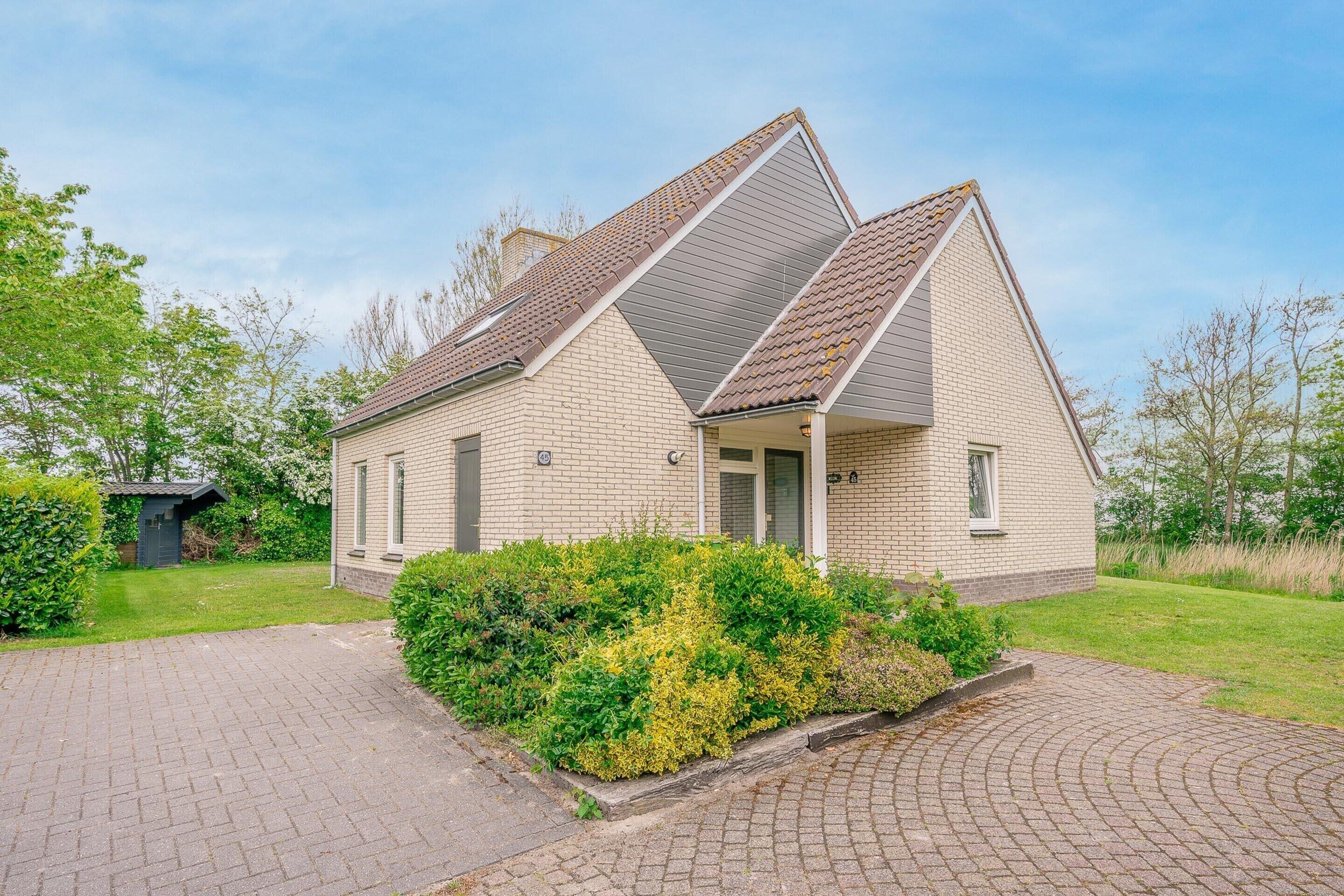 A single-story house with a sloped roof, a brick exterior, and a small front porch.