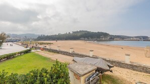 Une plage avec une promenade dallée, une zone herbeuse et un mur de pierres.
