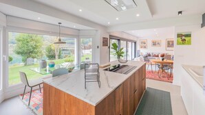 Une cuisine moderne dotée d’un îlot central, de grandes fenêtres et offrant une vue sur l’extérieur.
