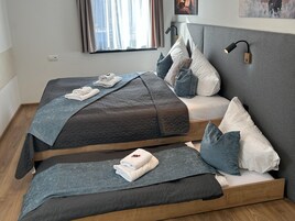Ein modernes Schlafzimmer mit zwei Betten, einem Nachttisch, einer Lampe und einem Fenster mit Vorhängen.