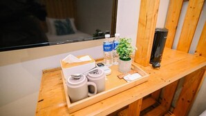 Une table de chevet en bois sur laquelle se trouve un plateau contenant des articles de toilette, une plante et une bouteille d’eau.