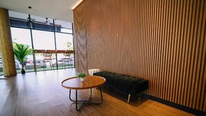 Un intérieur moderne avec une table ronde en bois, un canapé noir et des lambris en bois verticaux sur le mur.