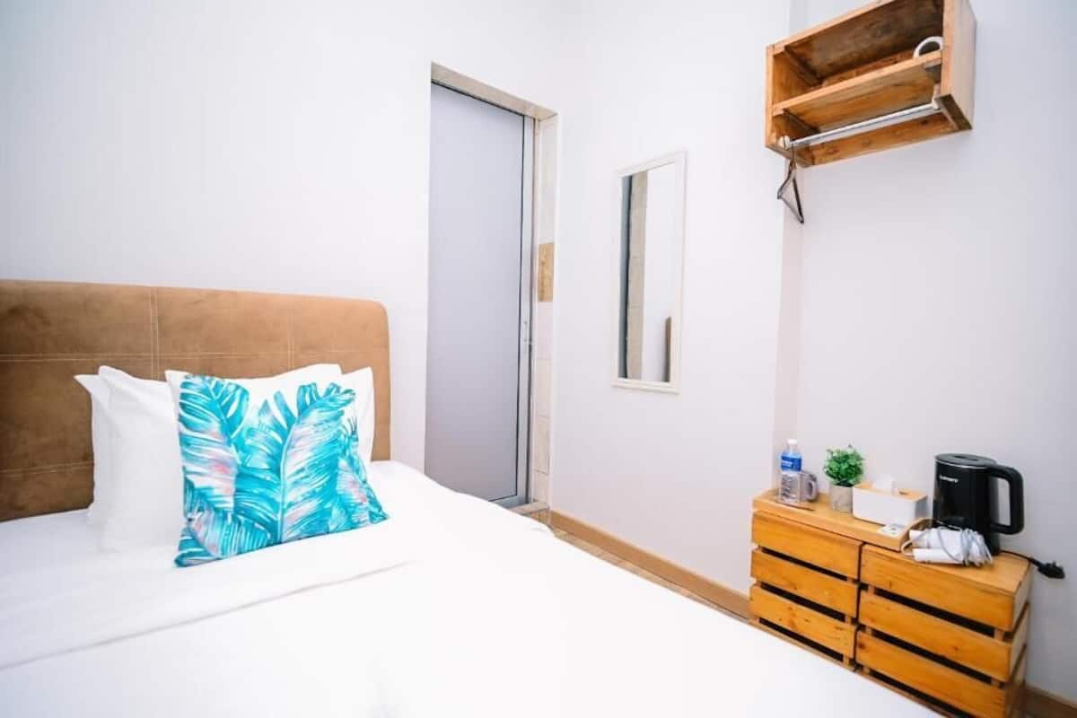 Una habitación de hotel con una cama, un aparador de madera, una cafetera y una planta pequeña.