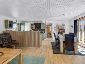 Una cucina moderna con mobili in legno, un'area pranzo con tavolo e sedie, e un soggiorno con divano e tavolino.
