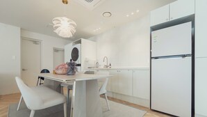 A modern kitchen with white cabinets, a built-in refrigerator, and a dining area with a table and chairs. - Ravenna. 5mis from Myeongdong/shopping/restaurant/beauty/skincare/suitefor10ppl (Seoul)