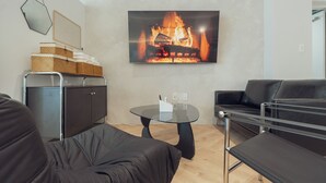 A modern living room with a fireplace, a sofa, a coffee table, and a black leather couch. - Ravenna. 5mis from Myeongdong/shopping/restaurant/beauty/skincare/suitefor10ppl (Seoul)